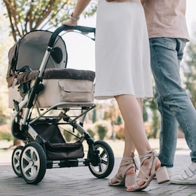 cropped image of parents walking with baby carriage in park