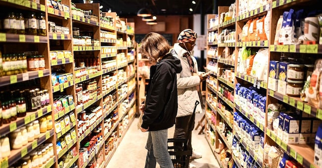 A student (L) shops for food products at a Biocoop food store before using a local digital currency known as "Gemme" to pay her bill, in Bordeaux, south-western France, on March 27, 2024. The endless hours spent waiting for a food aid parcel are now a distant memory for university students in Bordeaux, thanks to a Social Security for Food (SSA) card for their grocery shopping. (Photo by Christophe ARCHAMBAULT / AFP)