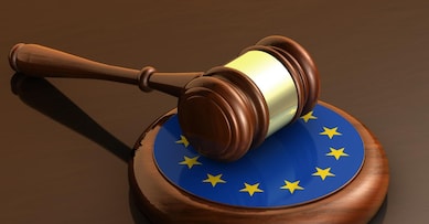 European Union laws, legal system and parliament concept with a 3d render of a gavel on a wooden desktop and the EU flag.