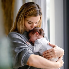 Loving mother hugs her little baby at home