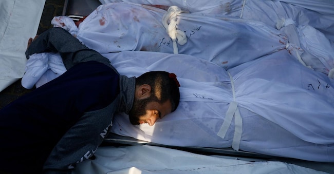 Sorge il giorno quando un sopravvissuto a un attacco aereo israeliano nel sud di Gaza, che era stato sfollato dalla città e aveva cercato rifugio con la famiglia nella città di Khan Younis, posa la testa sul cadavere di una parente di nome Tamam, che giace accanto ai membri della famiglia che sono stati uccisi durante lo sciopero, nell’ospedale Nasser, Khan Younis, Gaza, il 24 ottobre 2023. La scritta nella parte inferiore dell’immagine recita “Ghasan Ahmed Youssef Murad”. REUTERS/Mohammed Salem, Vincitore del premio Pulitzer per la fotografia settore Breaking News