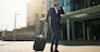 Business man, suitcase and phone call in city for professional communication, transport and travel news or information. Happy corporate worker with mobile chat, luggage and walking outdoor to airport.