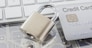 Close up metal padlock with silver credit card reflecting shadow on digital circuits and modern white keyboard on background. Online payment, banking data protection, security financial concepts.