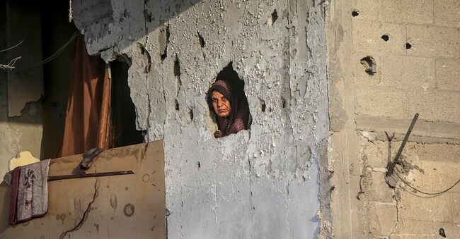 Una donna palestinese si affaccia dalla sua casa, distrutta dai bombardamenti israeliani a Khan Younis, nel sud della Striscia di Gaza (foto EPA/MOHAMMED SABER)