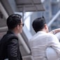 Asian businessman discuss with engineer architect in suite, looking and point to finger forward away and holding construction roll plan for working team concept,back view