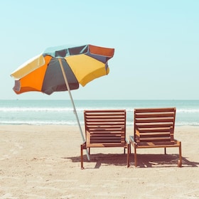 Vintage toned two beach chairs and umberella on empty tropical ocean beach at sunny day
