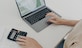 Cropped shot of unrecognizable woman sits at desk with laptop computer calculator and papers calculates montly expenses studies utility bills counts income uses e banking application plans investments