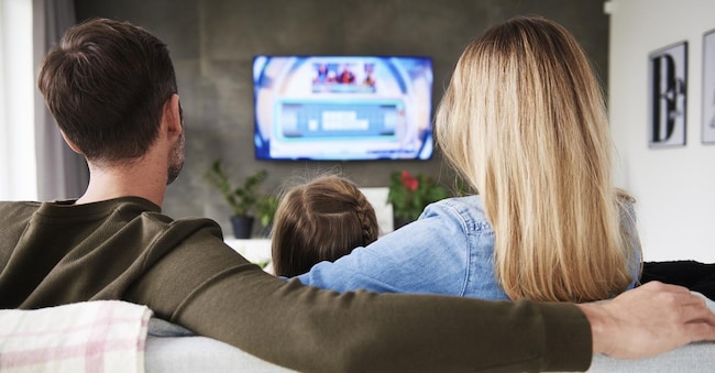 Rear view of family watching tv in living room