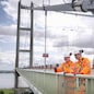 Bridge workers on parapet of suspension bridge. The Humber Bridge, UK was built in 1981 and at the time was the world's largest single-span suspension bridge