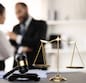 Balanced scale of justice and gavel hammer in focus on blurred background of lawyer colleagues discuss and plan for lawsuit in law firm office, as legal representatives. Equilibrium