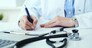 Mid section of female doctor writing prescription to patient at worktable.