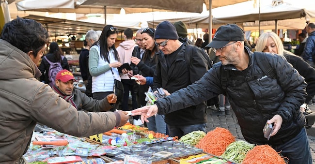 Turisti fanno acquisti in una bancarella a Campo de Fiori a Roma.
