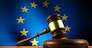 European Union law, legislation and parliament concept with a 3d rendering of a gavel on a wooden desktop and the EU flag on background.