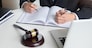 lawyer hand writes the document in court (justice, law) with sounding block.