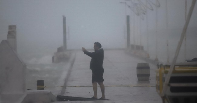 Una persona scatta una fotografia sotto la pioggia mentre l’uragano Milton passa vicino a Progreso, nello stato dello Yucatan, in Messico (AP)