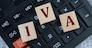 IVA (Individual Voluntary Arrangement) - acronym on wooden cubes on the background of a calculator. Business concept