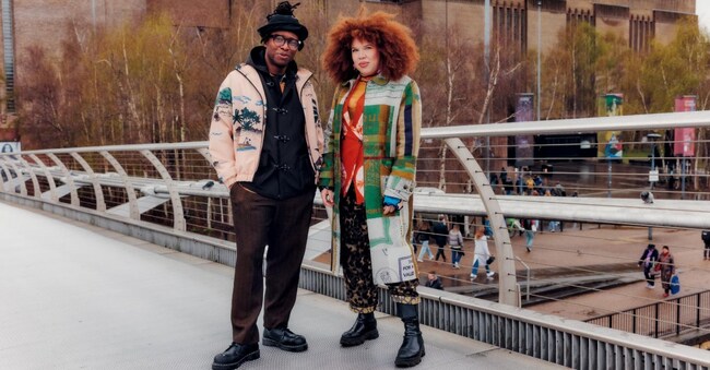 Foday Dumbuya (a sinistra) e Zezi Iforea Londra, davanti alla Tate Modern, dove si sono incontrati la prima volta. Lui indossa la tuta Freetown, lei il cappotto Maya Angelou Passport (1.535 €), tutto LABRUM.