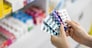 capsule in the women pharmacist hand and medicine shelf background in pharmacy store Thailand