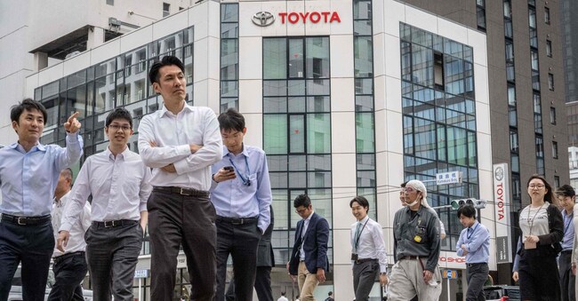 Pedoni davanti a una concessionaria della casa automobilistica Toyota a Tokyo. (Foto di Yuichi YAMAZAKI / AFP) (Photo by Yuichi YAMAZAKI / AFP)