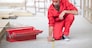 Builder with tool box and pencil measuring floor on construction site