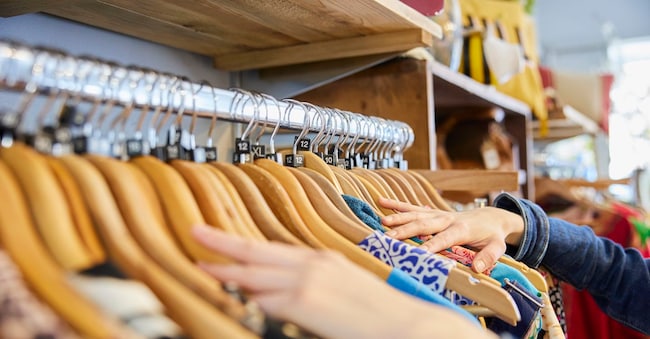 Close Up Of Young Woman Buying Used Sustainable Clothes From Second Hand Charity Shop
