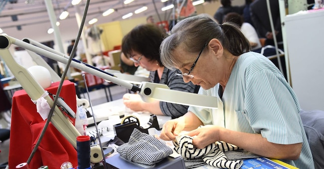 An employee sews clothing at the factory of French clothing brand Petit Bateau, in Troyes, on April 6, 2017.  / AFP PHOTO / bertrand GUAY