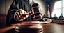 A judge's hand is poised to administer justice with a gavel in a courtroom, symbolizing the weight of judicial decisions