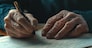 Close-up of an old man's hand studying and signing his last will and testament. Last will and testament concept