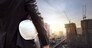White helmet of engineer architect holding by businessman in suit and building construction site background