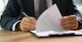 Businessman leafing through documents and signing contract for business deal at work in office closeup. Certification of documentation and control concept