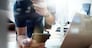 designer hand working and smart phone and laptop on wooden desk in office and two colleagues discussing data with london city background