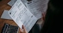 Close-up of female hands with pay slips, utility bills, account statements, payment receipts. A woman makes a count of household, family expenses with a calculator at home on the table.