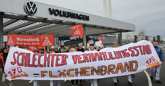 Dipendenti della Volkswagen manifestano con uno striscione del sindacato IG Metall che recita «Lo scarso stato delle trattative equivale a un incendio selvaggio» davanti allo stabilimento di Zwickau, dov si producono auto elettriche (Foto di Jens Schlueter / AFP)