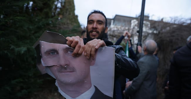 Un profugo siriano a Belgrado strappa un ritratto del presidente  Bashar al-Assad dopo la caduta del regime a Damasco