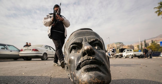 Un combattente dell’opposizione cammina accanto a un busto rotto del defunto presidente siriano Hafez Assad a Damasco, in Siria, domenica 8 dicembre 2024. (Foto AP/Hussein Malla)