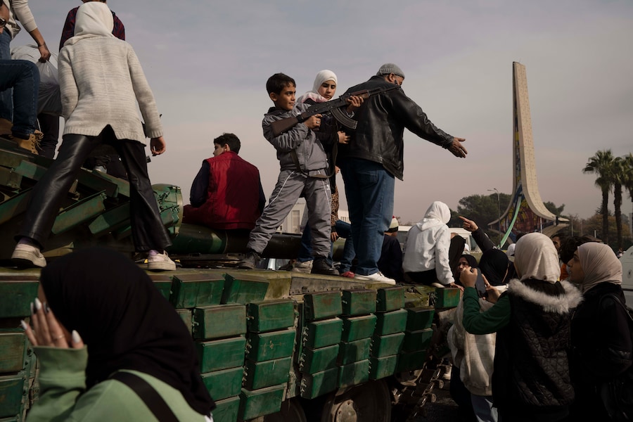 Un ragazzo con in mano un fucile preso in prestito da un combattente dell’opposizione siriana posa sul tetto di un carro armato delle forze governative lasciato in una strada, in Piazza degli Omayyadi a Damasco, in Siria, mercoledì 11 dicembre 2024. AP Photo/Leo Correa (APN)
