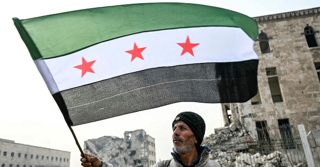 Un uomo con la bandiera dell’opposizione siriana davanti alla cittadella di Aleppo