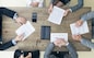 Business people discuss contract sitting around office table, top view