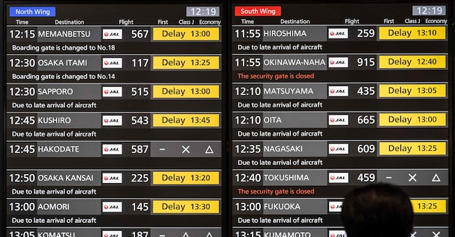 TOPSHOT - A man looks at a screen showing the delay of Japan Airlines flights at the departures hall of Haneda Airport in Tokyo on December 26, 2024. Japan Airlines on December 26 reported a cyberattack that caused delays to domestic and international flights but later said it had found and addressed the cause. (Photo by Yuichi YAMAZAKI / AFP)