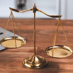 Symbolizing justice and legal authority, golden balanced scale on desk with laptop in law office background, reflecting concept of equality and fair judgment by lawyer and judge. equility