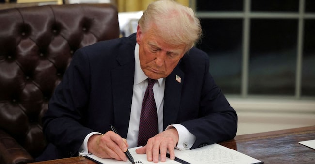 FILE PHOTO: U.S. President Donald Trump signs documents as he issues executive orders and pardons for January 6 defendants in the Oval Office at the White House on Inauguration Day in Washington, U.S., January 20, 2025.  REUTERS/Carlos Barria/File Photo