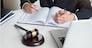 lawyer hand writes the document in court (justice, law) with sounding block.