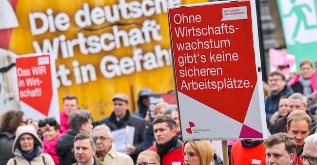 Una persona tiene in mano un cartello con la scritta “L’economia tedesca è in pericolo” e “Senza crescita economica, non ci sono posti di lavoro sicuri” durante una manifestazione nei pressi della Porta di Brandeburgo a Berlino, dove le associazioni imprenditoriali tedesche chiedono una svolta economica. (EPA/Hannibal Hanschke)