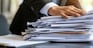 A businessman with a bundle of paper documents in hand.
