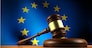 European Union law, legislation and parliament concept with a 3d rendering of a gavel on a wooden desktop and the EU flag on background.