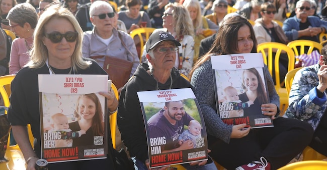 Persone che tengono foto di membri della famiglia Bibas durante una cerimonia di compleanno per il bambino israeliano Kfir Bibas, tenuto in ostaggio da Hamas a Gaza,e purtoppo morto insieme (Epa/Abir Sultan)