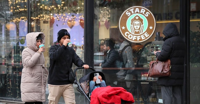 epa11910202 People with a baby stroller walk past the window of a 'Stars Coffee,' a chain that opened in former 'Starbucks' coffee shops, in Moscow, Russia, 20 February 2025. The American coffee chain Starbucks sold its business in Russia after the Russian president declared a 'special military operation' in Ukraine and the Western sanctions that followed it.  EPA/YURI KOCHETKOV