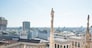 White statue on top of Duomo cathedral and view to city of Milan