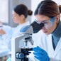 Young scientists conducting research investigations in a medical laboratory, a researcher in the foreground is using a microscope