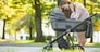 family, child and parenthood concept - happy mother walking with baby stroller in park.